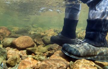 photo sous l'eau -  on voit les bottes d'un pêcheur